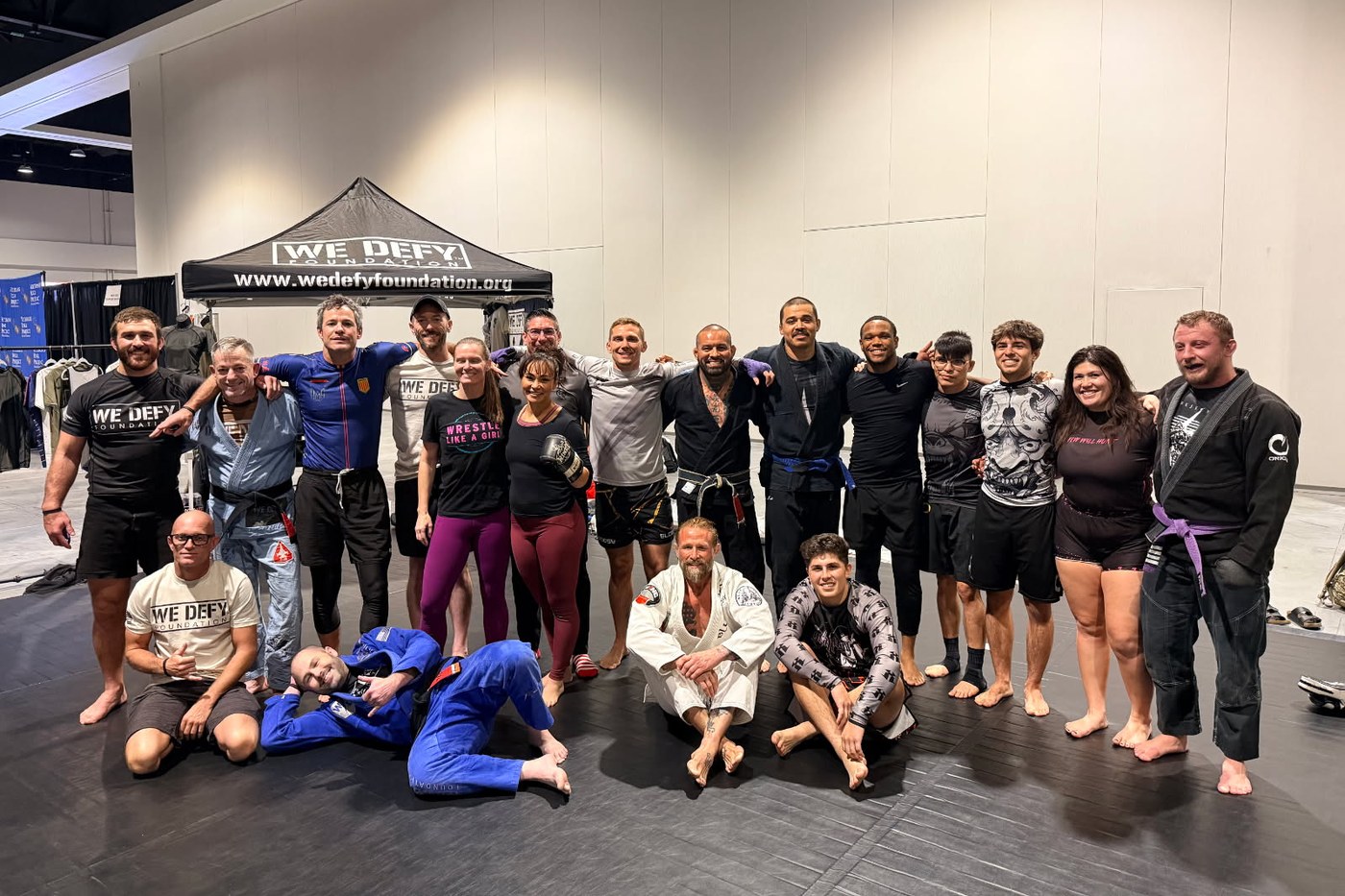 Competitors and coaches gathered on the mats under the We Defy Foundation tent at MCON 2025.